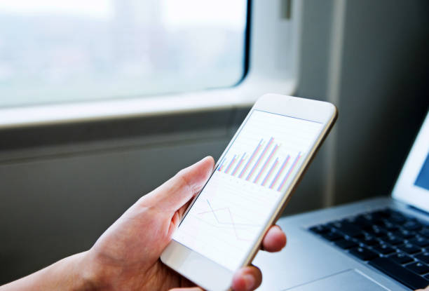 istock Woman using mobile phone and laptop on train 1182692091