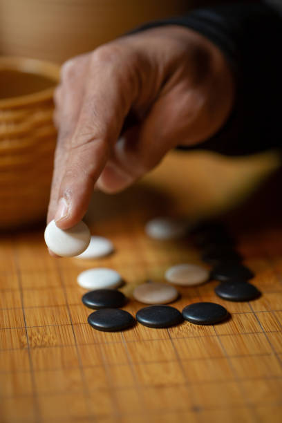istock Go board game playing. A competitor is placing a marble piece on a Go board game. 1182692268