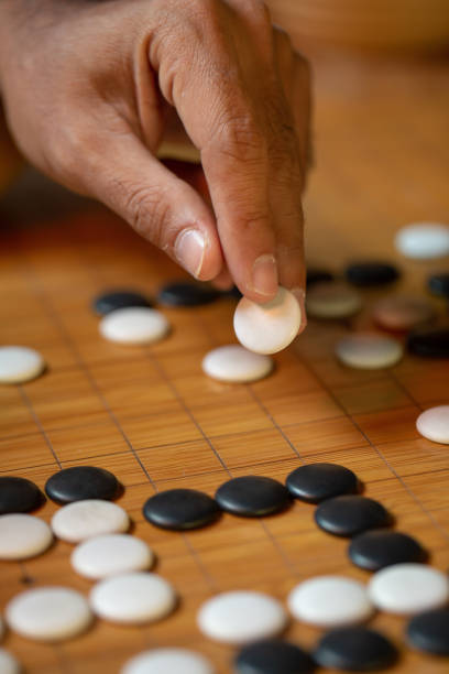 istock Go board game playing. A competitor is placing a marble piece on a Go board game. 1182692306