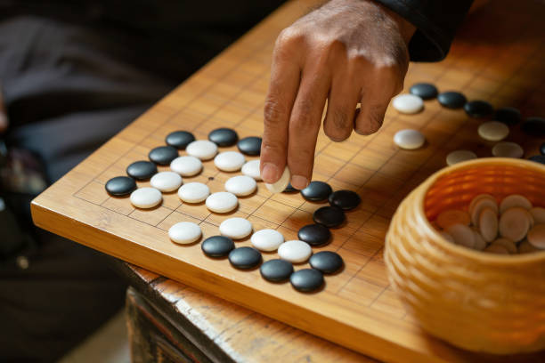 Go board game playing. A competitor is placing a marble piece on a Go board game.