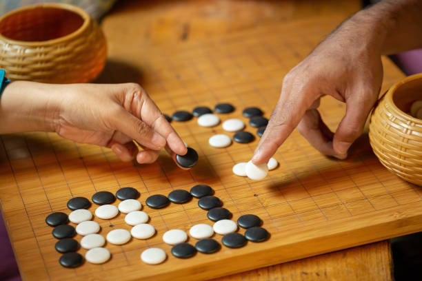 istock Go board game playing. A competitor is placing a marble piece on a Go board game. 1182692394