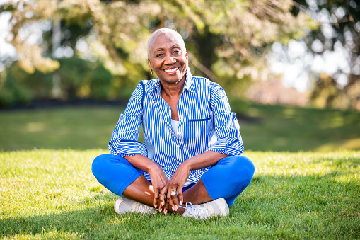 Active African American woman enjoying the nature, sitting on the grass, relaxing.