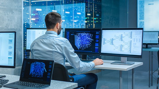 Hermosos ingenieros informáticos masculinos y científicos crean una red neuronal en su estación de trabajo. Office está lleno de pantallas que muestran representaciones 3D de redes neuronales. photo