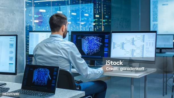 Beautiful Male Computer Engineer And Scientists Create Neural Network At His Workstation Office Is Full Of Displays Showing 3d Representations Of Neural Networks Stock Photo - Download Image Now