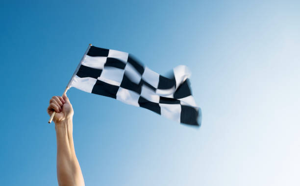 istock Man hand holding checkered flag in the wind 1182699881