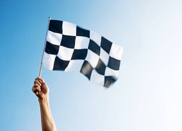 istock Man hand holding checkered flag in the wind 1182699933