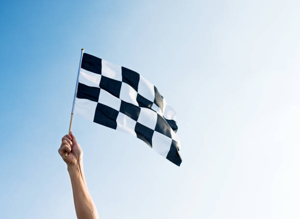 hombre mano sosteniendo la bandera a cuadros en el viento - checkered flag flag auto racing starting line fotografías e imágenes de stock