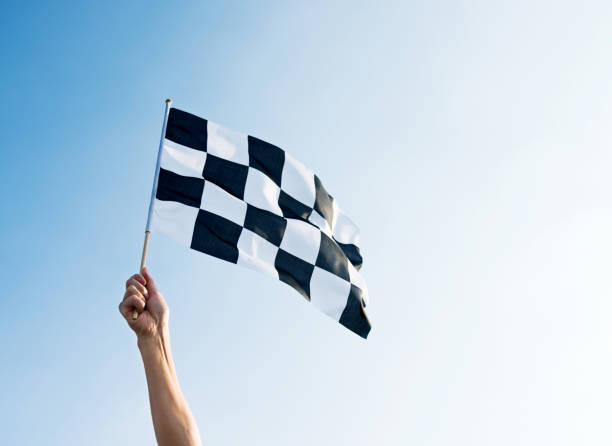 istock Man hand holding checkered flag in the wind 1182700149