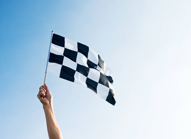 mão do homem que prende a bandeira checkered no vento - checkered flag flag auto racing starting line - fotografias e filmes do acervo