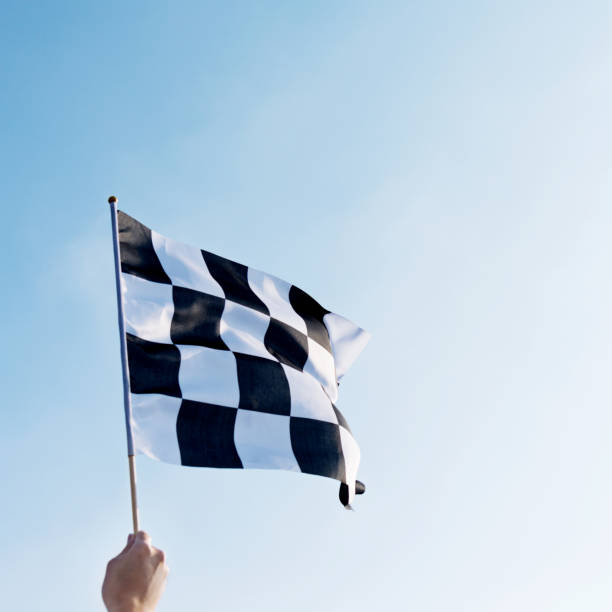 istock Man hand holding checkered flag in the wind 1182701056