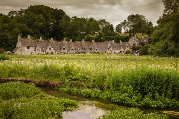 View of the famous houses of Arlington Row in the town of Bibury with the river Coln in the first place. The Cotswolds
