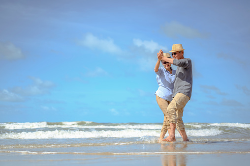 Senior couple  dancing on the beach on good days, plan life insurance at retirement concept.
