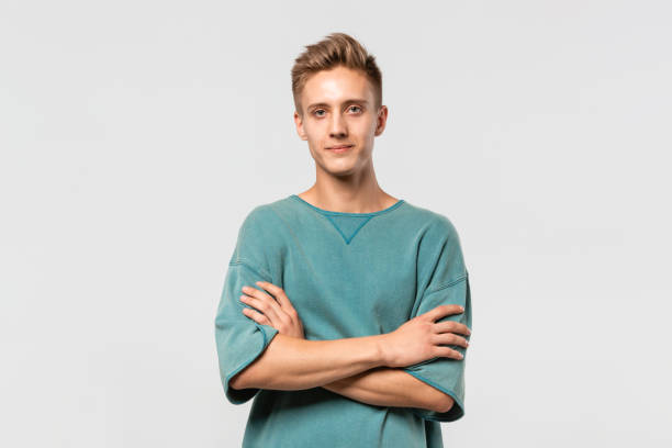 istock Confedent young man in a green tee holds hands folded isolated over grey background. 1182703155