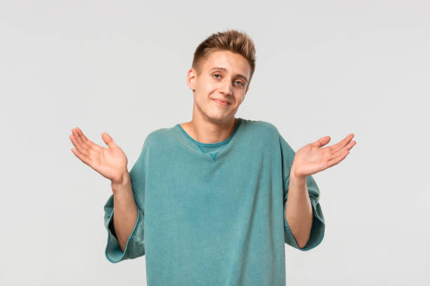 istock Young pretty man in a green tee shrugging shoulders being helpless. 1182703194