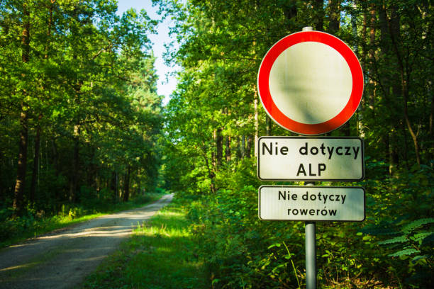 Road sign, no traffic in both directions, not applicable to the State Forests Administration, not applicable to bicycles. Text in Polish. Dirt road in the green forest