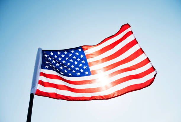 istock American flag waving against blue sky 1182703535
