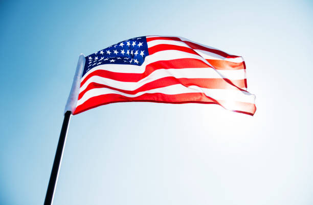 istock American flag waving against blue sky 1182703536