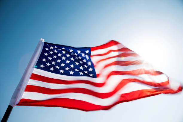istock American flag waving against blue sky 1182703743