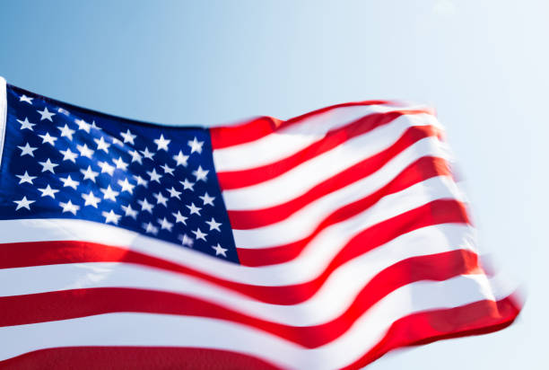 Close-up of American flag waving against blue sky.