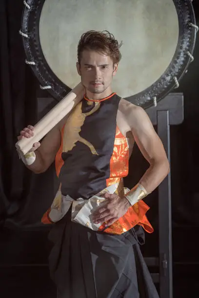 Photo of Portrait of a Japanese drummer Taiko with drumsticks on the background of a large drum.
