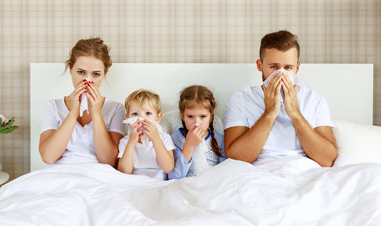 resfriados y enfermedades virales. familia con seno y fiebre en la cama photo