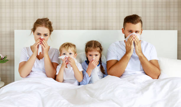 colds and viral diseases. family with runny nose and fever in bed colds and viral diseases. family with runny nose and fever in bed at home child liquid medicine stock pictures, royalty-free photos & images