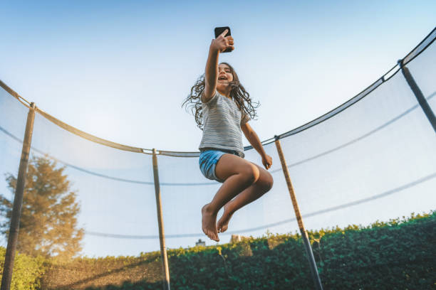 istock little girl jumping high on trampoline with mobile 1182714164