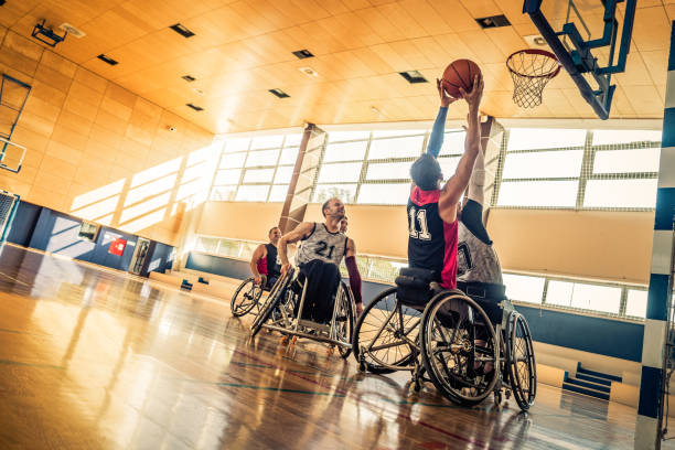 Attempting a block during a wheelchair basketball game Player attempting to block another players throw in a game of wheelchair basketball in a gymnasium. adaptive athlete stock pictures, royalty-free photos & images