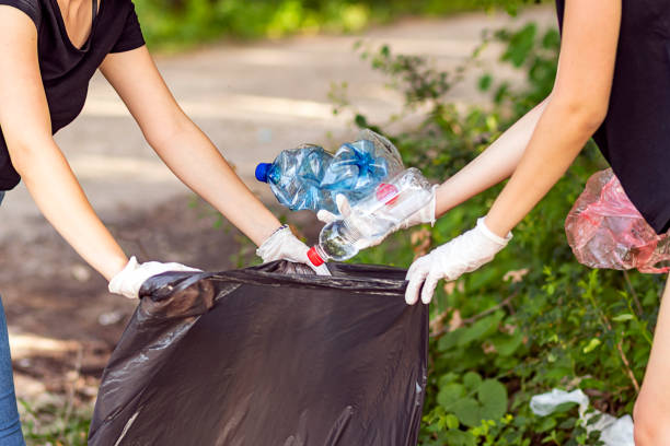 Woman hand picking up garbage plastic for cleaning at park stock photo