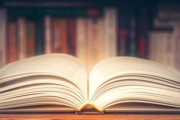 istock Open book closeup with blurry boolshelf in the background. Toned image with dreamy look. Literature, reading, knowledge, study, novel, literacy concept. 1182718746