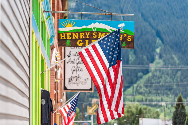 Small village famous old town sign for henry smith's gifts store shop with American Flag Silverton, USA - August 14, 2019: Small village famous old town sign for henry smith's gifts store shop with American Flag on sunny summer day in Colorado multi colored wild west photograph american flag stock pictures, royalty-free photos & images
