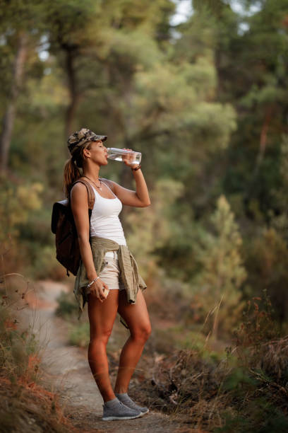 istock Young woman drinking water while hiking through nature. 1182720017