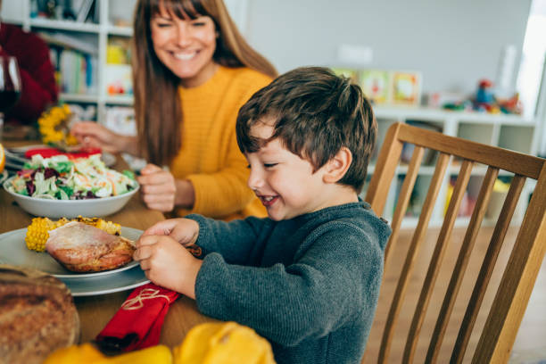 Happy mother and her son having fun while eating turkey leg