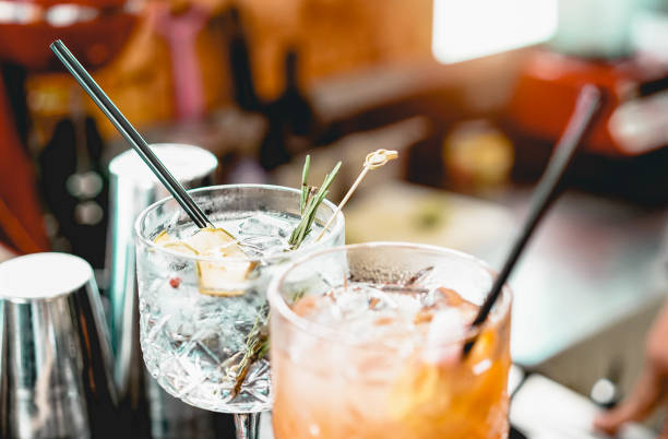 cócteles servidos en el mostrador de bar preparados con ginebra, romero, papel y jugo de naranja - bebida, vida nocturna, concepto de estilo de vida - enfoque en cristal superior - non alchoholic berverage fotografías e imágenes de stock