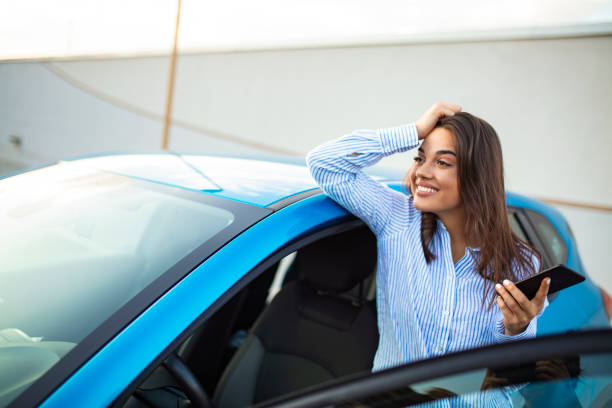 istock Business Woman Uses Smartphone While Leaning on Her Car 1182724628