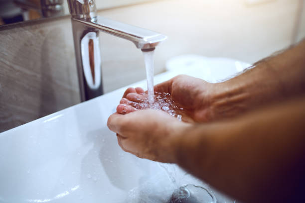 istock Close up male cupped hands under tap in bathroom. Morning routine. 1182727619