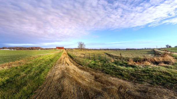 paisagem agrícola de uma exploração agrícola rural de maryland com estrada de terra longa que conduz a um celeiro vermelho - road long dirt footpath - fotografias e filmes do acervo