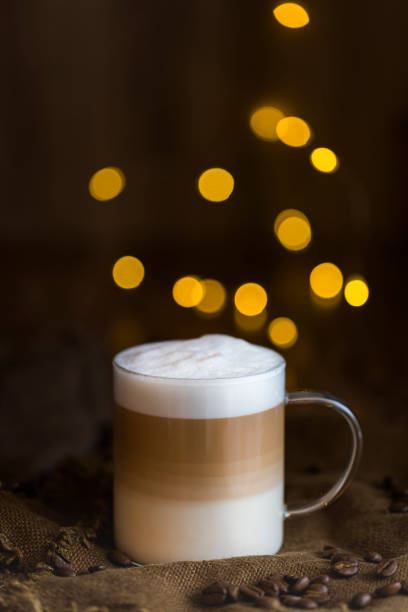 istock Cafe latte macchiato layered coffee in a glass cup with string lights in the background 1182729064