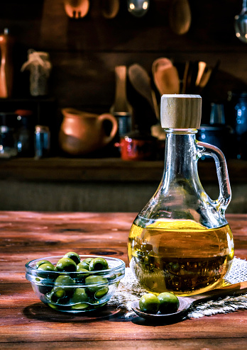 Olive oil bottle with olives. Arrange on table in old fashioned rustic kitchen.