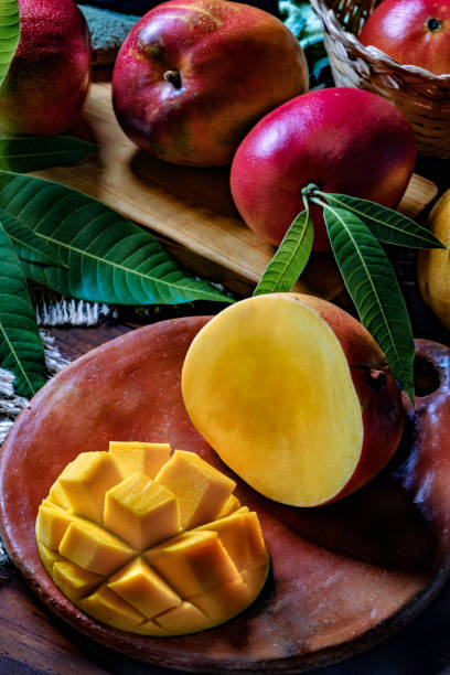 istock Tropical Fruits: Sliced mangos in a clay rustic plate on a wooden table in rustic kitchen 1182735844