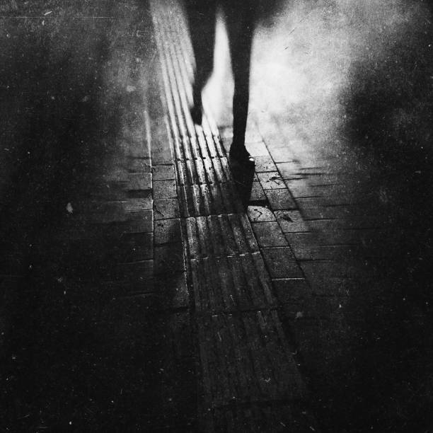 Monochrome textured view of a woman walking at the night Shot and edit on iPhone woman alone dark shadow stock pictures, royalty-free photos & images