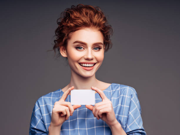 mujer joven sosteniendo una tarjeta de visita - smiling business card horizontal women fotografías e imágenes de stock