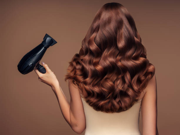 dziewczyna z piękną fryzurą trzymającą suszarkę do włosów - women long hair rear view beauty zdjęcia i obrazy z banku zdjęć