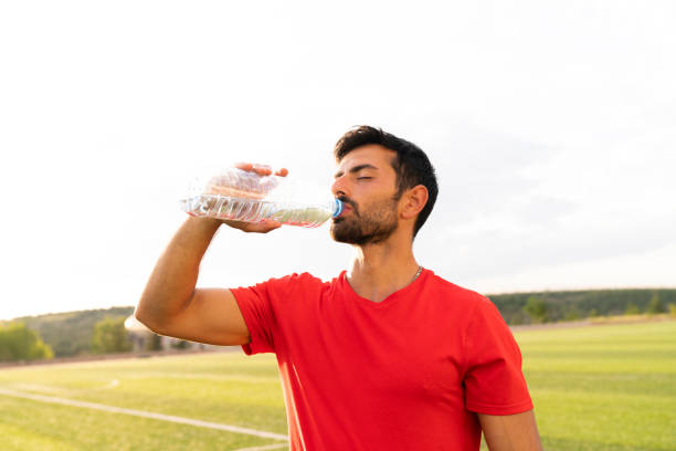 istock handsome male athlete drinking water after training 1182747839