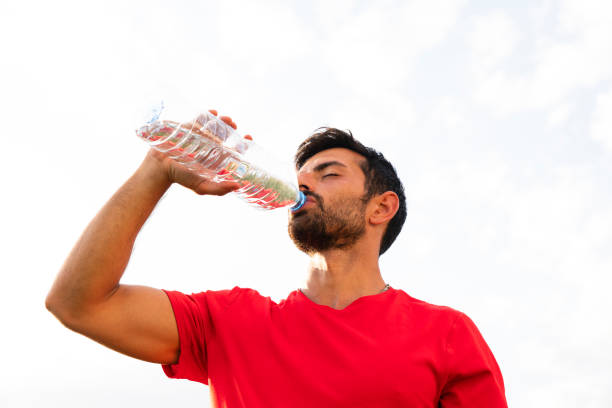 istock handsome male athlete drinking water after training 1182747841