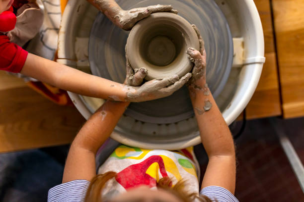 istock Close up of four hands working on potters wheel 1182747979