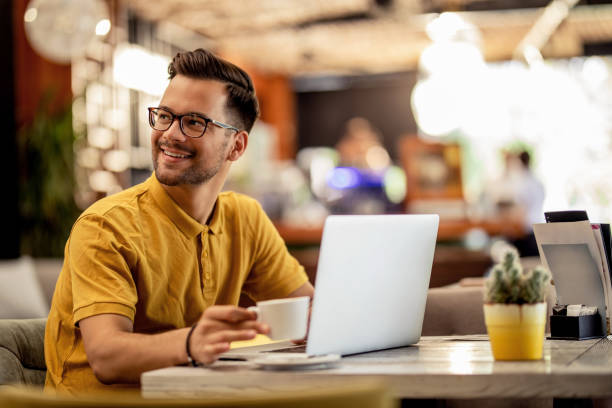 istock Smiling man enjoying in coffee break while using laptop in a cafe. 1182753094