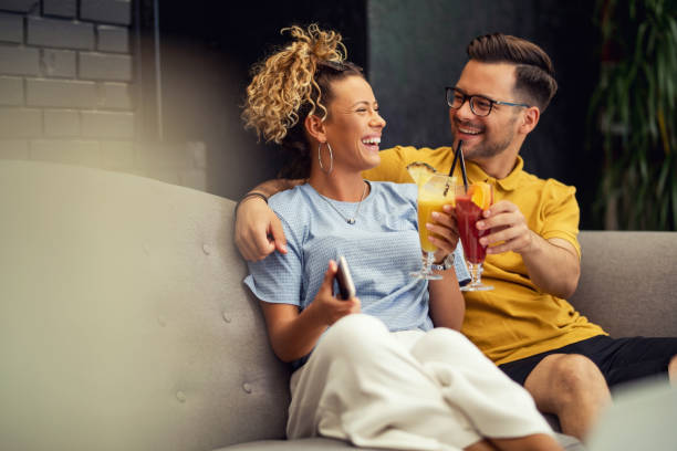 feliz pareja tosando con cócteles de frutas en una cafetería. - home interior cocktail bar women fotografías e imágenes de stock