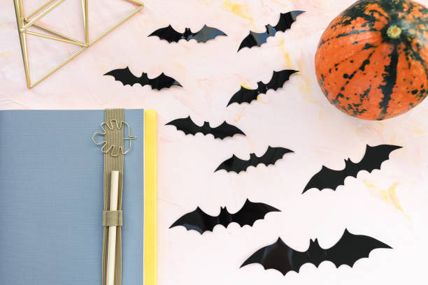 istock Notebook, pen, pumpkin and bats on a pink background. Halloween concept. 1182758914