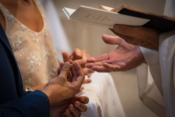 istock groom in the church putting wedding ring 1182758936